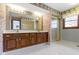 Vintage bathroom with double sinks, wallpaper, and a glass-enclosed shower at 10817 Lakeview Dr, Carmel, IN 46033