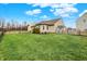 Landscaped backyard with a well-manicured lawn, wooden fence, and mature trees under a blue sky at 129 W Clear Lake Ln, Westfield, IN 46074
