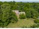Aerial shot showcases a home with a well-manicured lawn, surrounded by mature trees, offering privacy and curb appeal at 1409 S Harmony Trl, Greenfield, IN 46140