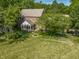 Aerial view displays the back of a brick home featuring a screened porch, fountain, and a garden, set on a well-kept lawn at 1409 S Harmony Trl, Greenfield, IN 46140