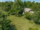 Aerial view of a brick home with large backyard, mature trees, American flag, and a quaint garden, creating a peaceful retreat at 1409 S Harmony Trl, Greenfield, IN 46140