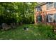 Spacious backyard with lush green grass, mature trees, garden and the brick house at 1409 S Harmony Trl, Greenfield, IN 46140