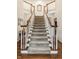 Grand foyer showcasing a staircase with wood railings, white trim, and neutral carpeting at 1409 S Harmony Trl, Greenfield, IN 46140