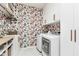 Laundry room with floral wallpaper, white cabinets, and modern front load washer and dryer units at 15104 Midland Ln, Noblesville, IN 46062