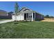Landscaped front yard featuring a newly planted tree, fresh sod and a cozy covered porch on a sunny day at 2254 Oakmont Dr, Plainfield, IN 46168