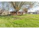 A spacious backyard with mature trees and green grass surrounding a charming single-story brick home at 4113 Gambel Rd, Indianapolis, IN 46221