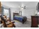Spacious bedroom features a wood bed frame, plush carpet, a ceiling fan, and decorative armchairs at 4501 N Wheeling Ave # 6A - 201, Muncie, IN 47304