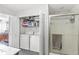 Well-lit laundry area with modern appliances, shelving for storage, and a view of the adjacent shower at 481 Autumn Springs Ct, Avon, IN 46123