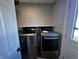 Modern laundry area with stainless steel washer and dryer, storage, and a doorway leading outside at 5061 N 200 W, Columbus, IN 47201