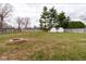 Large fenced backyard featuring a stone firepit and two white sheds at 518 Wedgewood Dr, Anderson, IN 46013