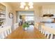 Bright dining room with a long wooden table, white chairs, and view into the living room at 518 Wedgewood Dr, Anderson, IN 46013