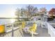 Sunny deck with lake views, yellow chairs and tables offering a relaxing outdoor space at 7780 Paw Paw Dr, Nineveh, IN 46164