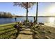 Scenic lakeside fire pit area with stone walkway, Adirondack chairs, and peaceful water views at 7780 Paw Paw Dr, Nineveh, IN 46164