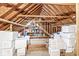 Unfinished attic space with exposed rafters and wood beams, featuring storage shelves filled with boxes at 8425 N Halyard N Way, Indianapolis, IN 46236