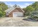 A two car garage with a brick exterior and concrete driveway is nestled amongst mature trees at 8425 N Halyard N Way, Indianapolis, IN 46236