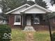 Charming brick home featuring a covered front porch with decorative ironwork and mature trees at 923 N Denny St, Indianapolis, IN 46201