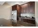Stylish bar area featuring dark wood cabinetry, granite countertops, a stainless steel refrigerator, and glassware display at 995 Westlake Hills Dr, Columbus, IN 47201