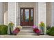 Elegant front door with decorative glass, surrounded by colorful potted flowers and lush greenery at 995 Westlake Hills Dr, Columbus, IN 47201