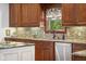Detailed view of kitchen sink with granite counters, tile backsplash, and wood cabinets at 995 Westlake Hills Dr, Columbus, IN 47201