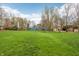 Spacious backyard showcases a large grassy area, complemented by a charming blue house and mature trees at 1250 W 141St St, Carmel, IN 46032
