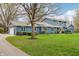 View of a blue house with a mature tree in the front yard, complemented by trimmed hedges and lush green grass at 1250 W 141St St, Carmel, IN 46032