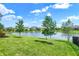 Tranquil backyard featuring a serene pond view, vibrant green grass, and young trees at 1499 Avondale Dr, Westfield, IN 46074