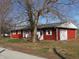 Charming red home featuring white trim, a well-manicured lawn, and a picturesque tree in the front yard at 210 Evergreen St, Morgantown, IN 46160
