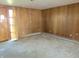 Large living area with paneled walls, neutral carpet and radiator-style heating along the baseboards at 210 Evergreen St, Morgantown, IN 46160