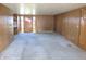 Spacious living room featuring paneled walls, neutral carpet and a welcoming front door at 210 Evergreen St, Morgantown, IN 46160