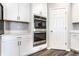 Kitchen with stainless steel double ovens, quartz counters, gray backsplash, white cabinets, and wood flooring at 2352 Somerset Cir, Franklin, IN 46131