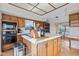 Well-lit kitchen featuring a center island, wood cabinets, and black appliances at 241 Melissa Ann Ct, Indianapolis, IN 46234