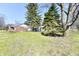 Backyard with two large evergreens and a two-story brick and light-colored home at 302 S Sherman Dr, Indianapolis, IN 46201