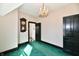A bedroom featuring a chandelier, green carpet, and an antique clock with view to another room with a black and white floor at 302 S Sherman Dr, Indianapolis, IN 46201