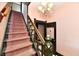 This carpeted stairway has a wooden banister and chandelier overhead at 302 S Sherman Dr, Indianapolis, IN 46201