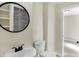 Bathroom featuring a modern round mirror, gray tile, and a white sink at 39 S Holmes Ave, Indianapolis, IN 46222