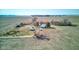 An aerial view of a farmhouse and green-roofed outbuilding in a rural area surrounded by fields, trees, and a gravel driveway at 4254 N 200 W, Greenfield, IN 46140