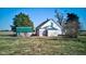 Charming farmhouse with green roofed sheds and mature trees against a clear blue sky at 4254 N 200 W, Greenfield, IN 46140
