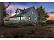 Charming two-story home with green roof, deck, and neatly stacked woodpile, set against a colorful sunset at 4254 N 200 W, Greenfield, IN 46140