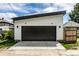 Exterior view of modern garage with white siding, black doors, and a concrete driveway at 632 N Temple Ave, Indianapolis, IN 46201