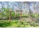 Backyard with a blue swing set among mature trees and lush greenery at 8220 Traders Hollow Ct, Indianapolis, IN 46278