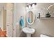Bright powder room features pedestal sink, updated fixture, and decorative mirror at 8233 Katrina Way, Fishers, IN 46038