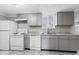 Functional kitchen with gray cabinets, white appliances, and a window above the sink at 866 W 29Th St, Indianapolis, IN 46208
