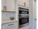 Stainless steel double ovens are built into the white cabinetry with subway tile backsplash and granite countertops at 12073 Springtide Ln, Fishers, IN 46037