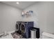Well-lit laundry room with modern washer, dryer, and shelving unit at 12073 Springtide Ln, Fishers, IN 46037