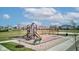Community playground with swings, slides, and benches surrounded by a grassy area and a sidewalk at 12073 Springtide Ln, Fishers, IN 46037