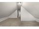 Slanted attic bedroom with neutral walls and carpet, window, and an open doorway at 1211 W 30Th St, Indianapolis, IN 46208