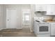 Bright kitchen with white cabinets and appliances, featuring vinyl floors at 1211 W 30Th St, Indianapolis, IN 46208