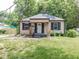 Charming home with dark shutters, covered porch, and a lush green yard, nestled among mature trees at 1707 N Leland Ave, Indianapolis, IN 46218