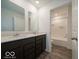 Bright bathroom features a double vanity, dark cabinets and a tub with white tile surround at 2290 Oakmont Dr, Plainfield, IN 46168