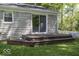 A quaint back deck leads to a sliding glass door entry on a home with stone siding and a well-maintained yard at 6204 S Madison Ave, Indianapolis, IN 46227